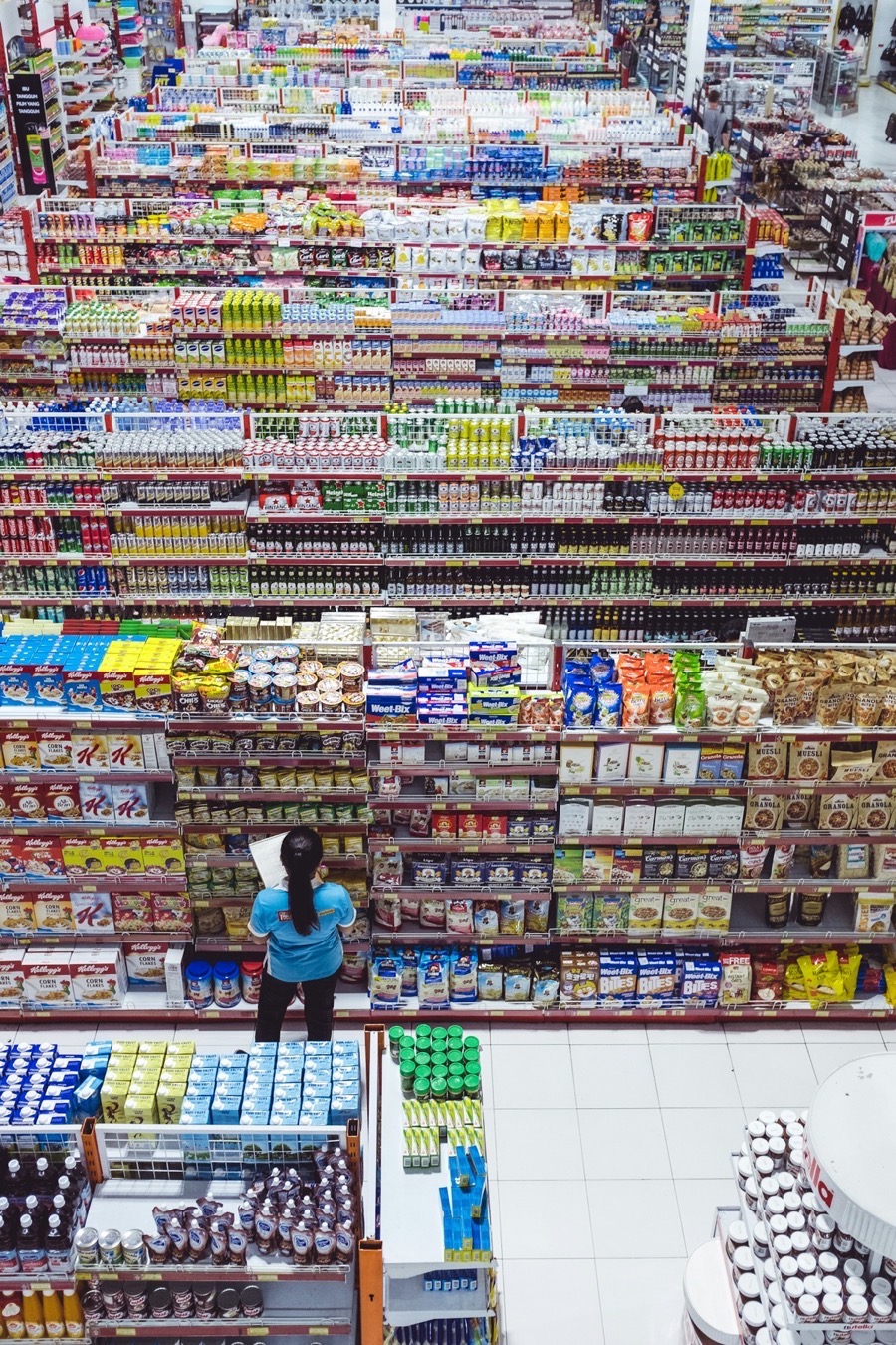 A shopper comparing products and price labels across a supermarket category
